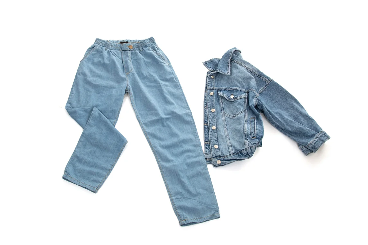 Denim jeans and jacket flat lay with a shadowed studio background before AI background removal