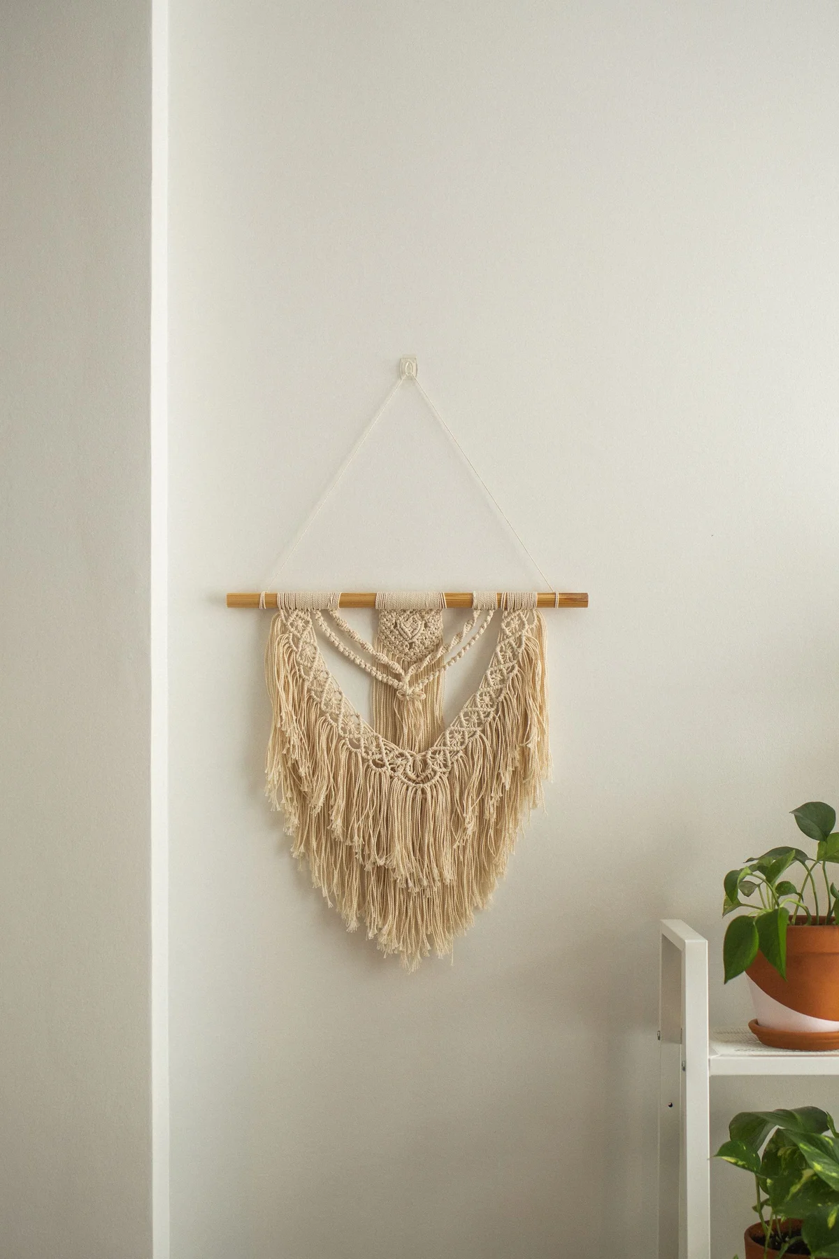 Handmade macramé wall hanging photographed in a room before AI background removal