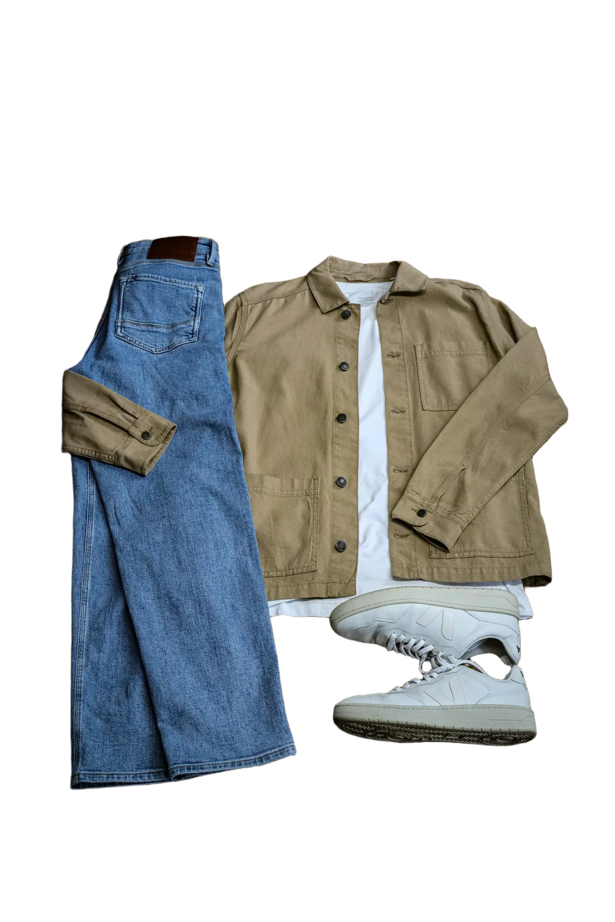 Apparel flat lay with the background removed for a Shopify store listing — jeans, jacket, tee, and sneakers isolated on transparency