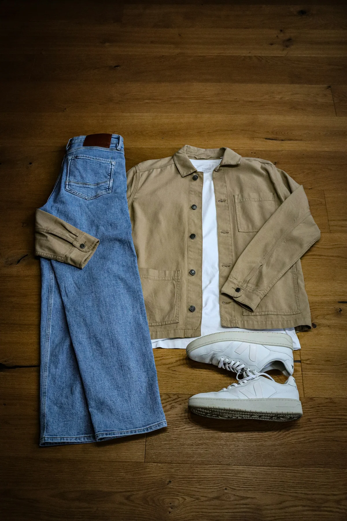 Apparel flat lay photographed on a wooden floor before AI background removal